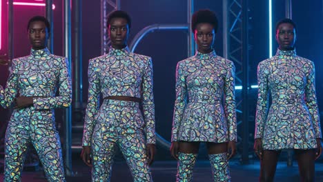 a stunning showcase of fashion: four models strut in vibrant patterned outfits under neon lights, capturing the essence of modern style and elegance