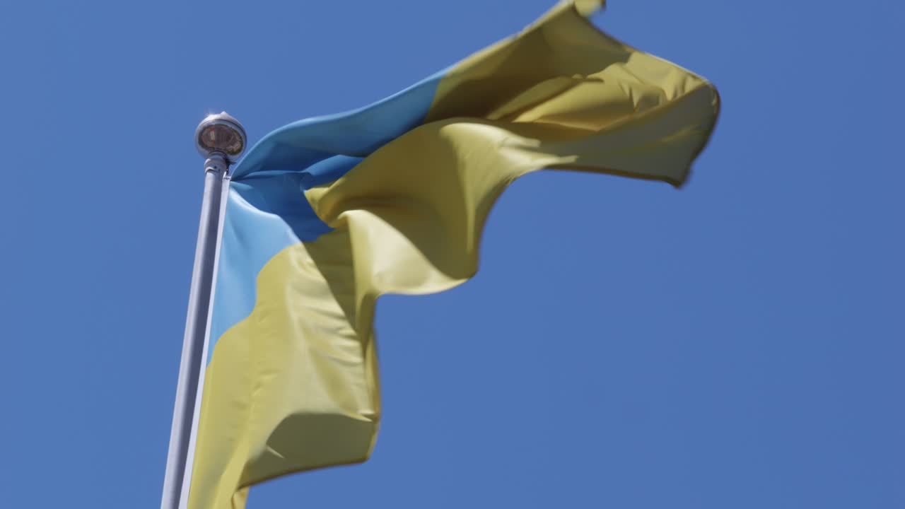 La bandiera ucraina sventola contro il cielo blu limpido