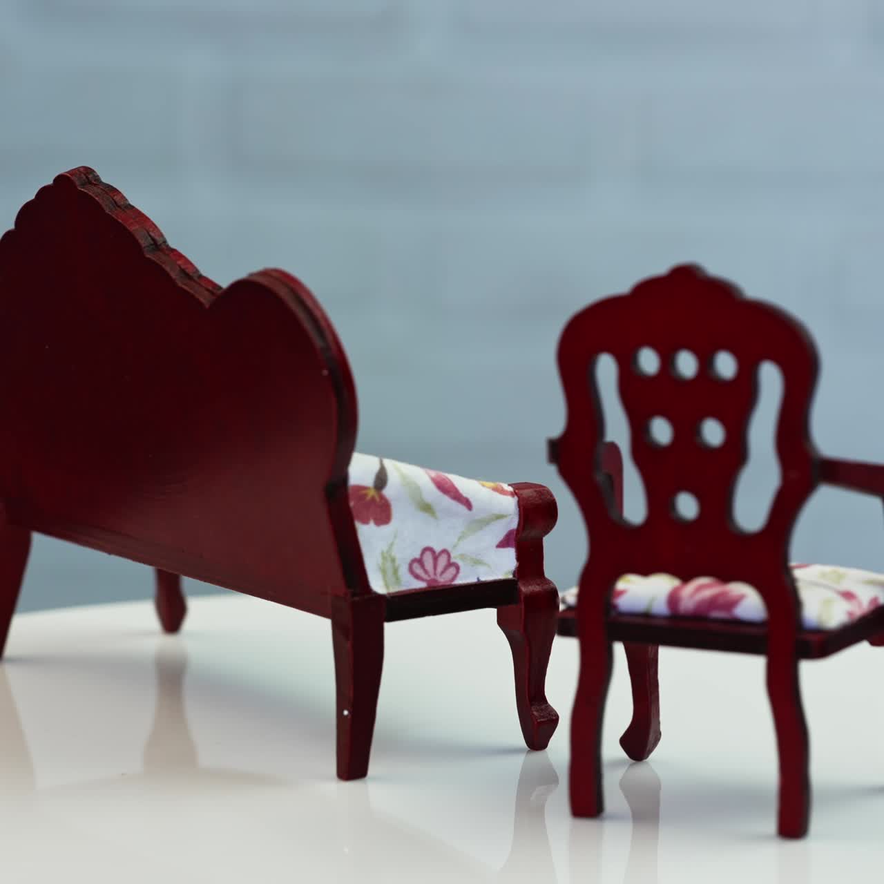 Lovely curved wooden furniture from doll's house. Toy sofa and chair with bright fabrics cover. Samples on the rotating table close up