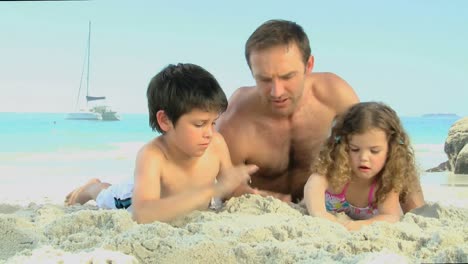 el hombre y sus hijos construyendo un castillo de arena