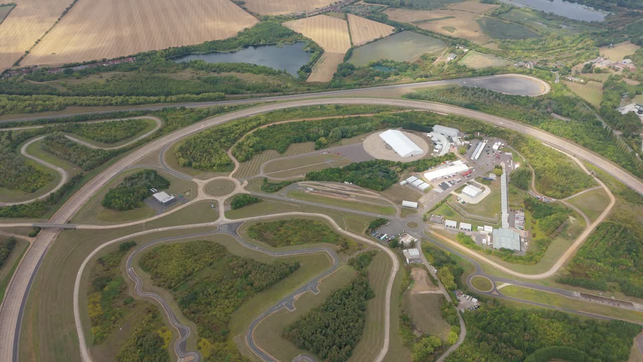 Wide aerial panorama of Bedford England automotive proving grounds showing vehicle testing tracks, car research facilities and rolling rural countryside