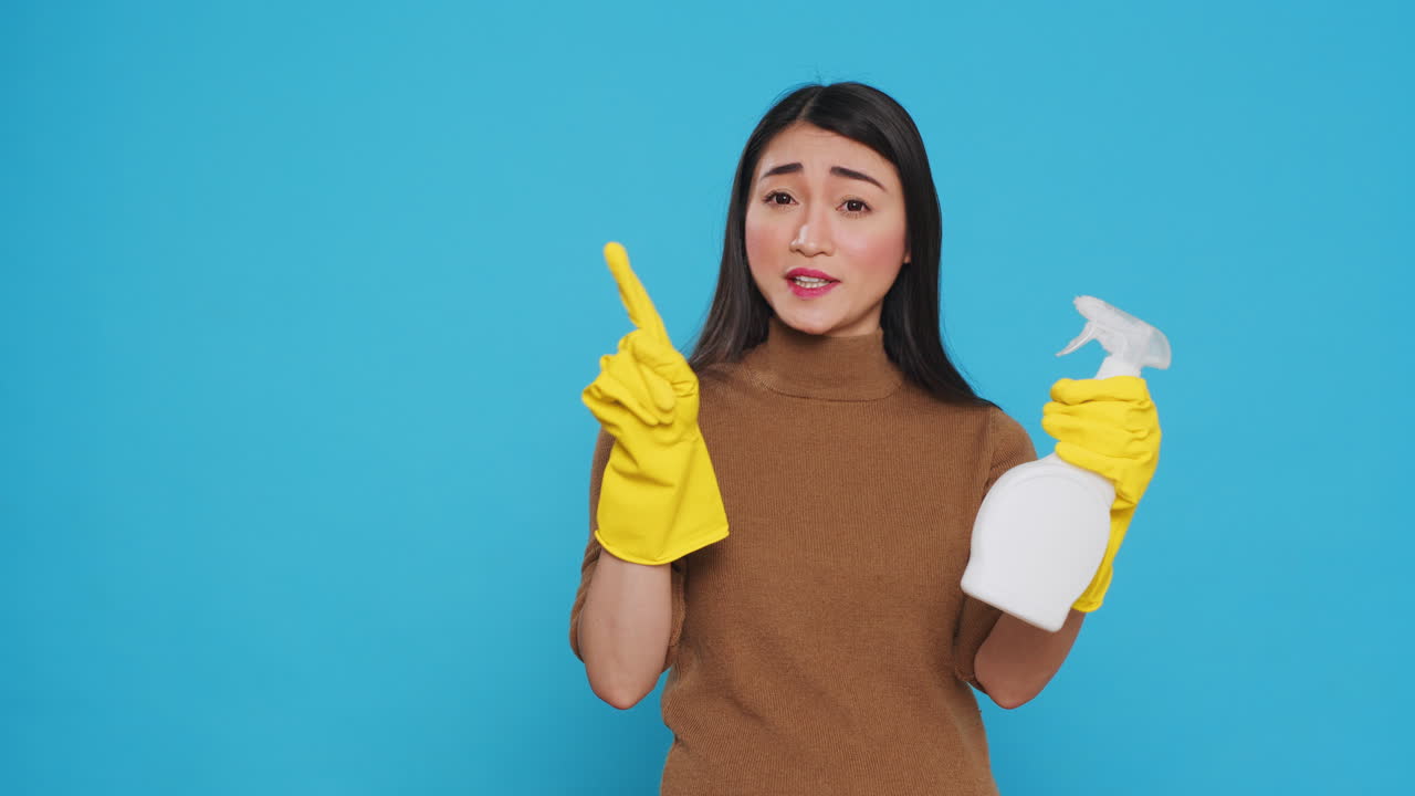 Professional maid pointing and showing cleaning product or isolated text