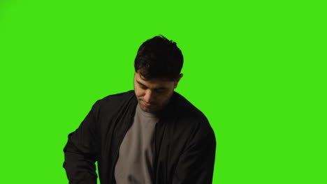 Young-Man-Getting-Alert-And-Looking-At-Text-Message-On-Mobile-Phone-Standing-Against-Green-Screen-1