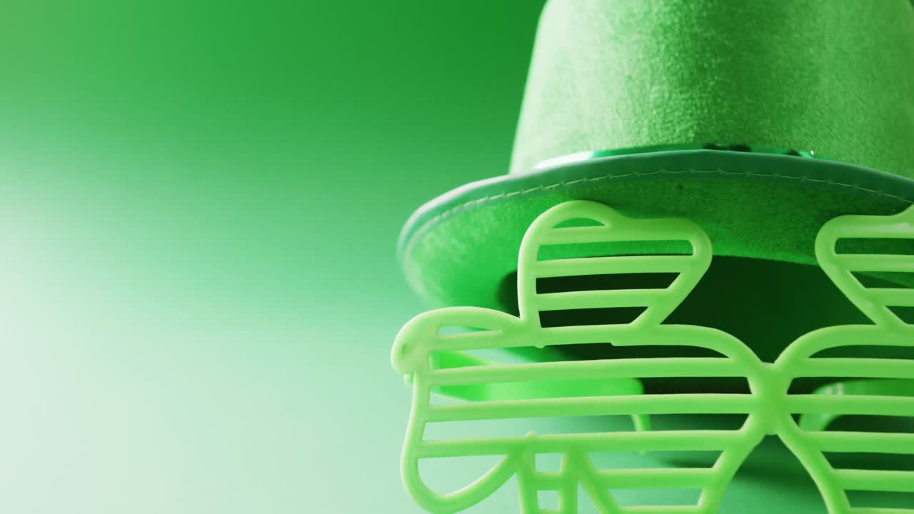 Video of st patrick's shamrock leaf glasses and hat with copy space on green to white background