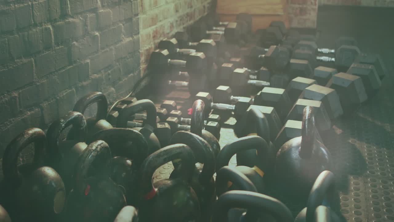 Camera starting pullback and panning right, kettlebells staying front while revealing gym layout