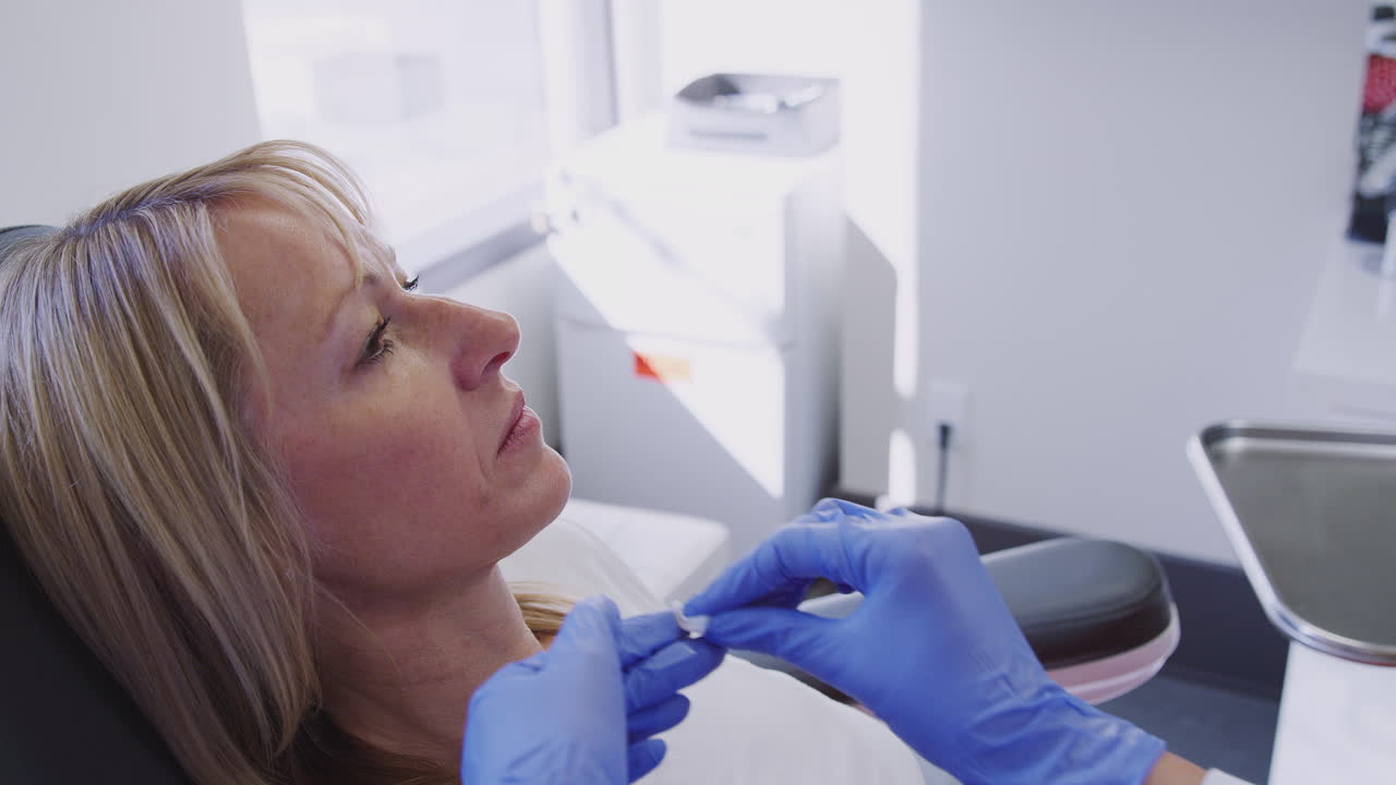 primer plano de un esteticista o médico limpiando la cara de una mujer después de la inyección de botox