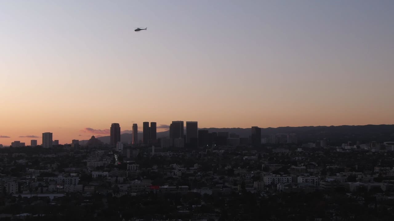 Helicopter flyover Los Angeles Downtown skyline during sunset, Aerial Descending shot