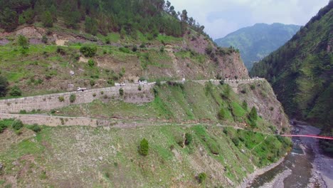 Highway-at-the-top-of-the-mountain-and-a-river,-Nepal,-Traffic-on-the-road,-Hill-with-trees-and-forest,-drone-shot,-camera-going-down