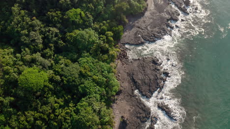 top down camera aerial 4k drone shot of rocky beach with wavy sea in tambor, costa rica