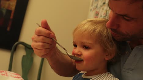 father feeding baby at home in 4k. parent nourishing toddler boy. baby pointing at something
