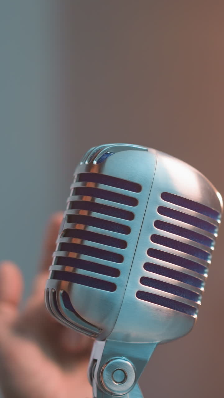 vista lateral de cerca de una mujer con un sombrero negro soplando un beso a un micrófono vintage con una sonrisa, contra un fondo borroso con iluminación cálida, capturando un momento íntimo y emotivo