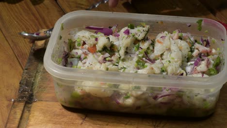 close-up of fresh ceviche with olive oil being added, rustic wooden table