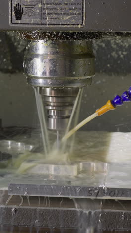 máquina de fresado cnc en acción con pulverización de refrigerante en la parte metálica durante el mecanizado