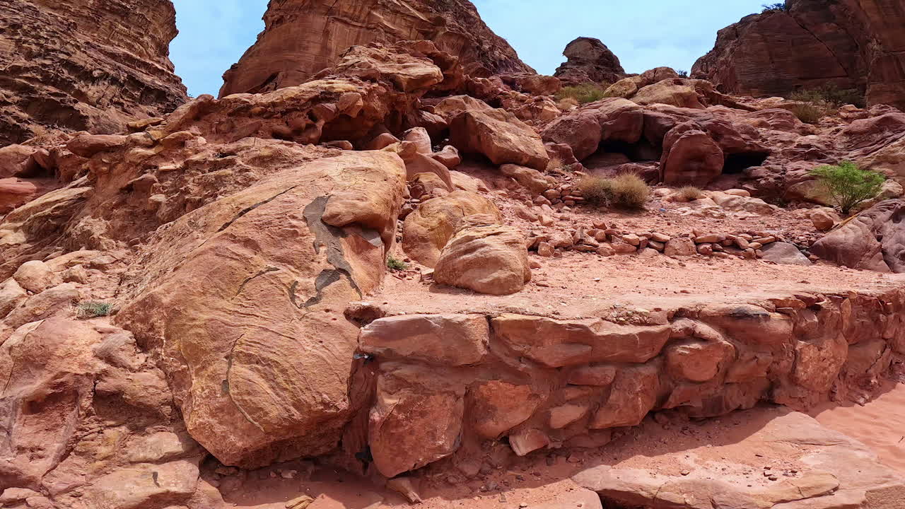 Stones, boulders and scarce vegetation in the canyons of Sinai Desert. Low angle view at the rocks of Petra, Jordan, West Asia.