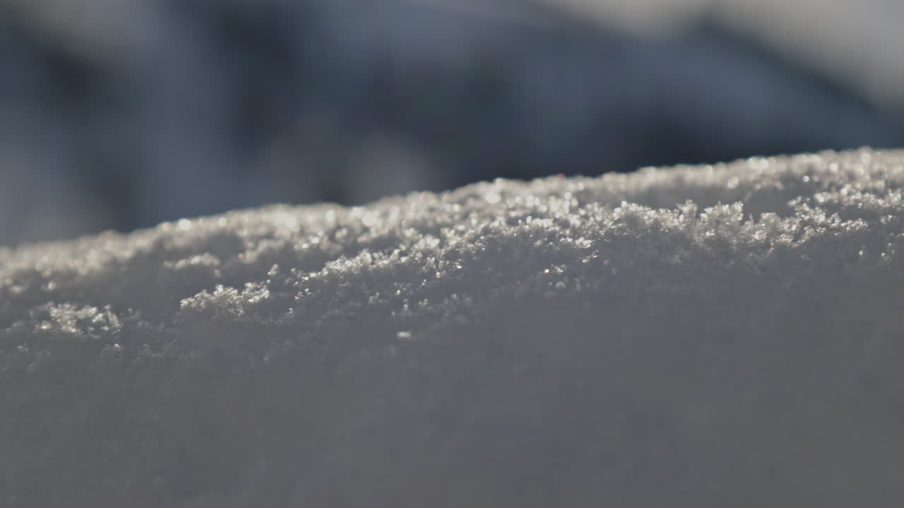 Detailed close-up of a luxury snow wall in Switzerland, with sparkling snow crystals glistening under bright sunlight on a clear winter day