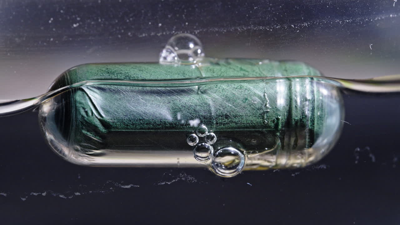 Pill dissolving in liquid, bubbles forming around the dissolving capsule