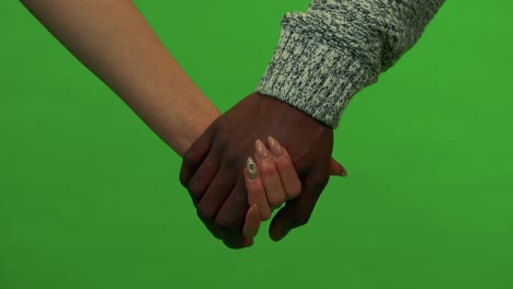 an asian woman and a black man hold hands - closeup - green screen studio