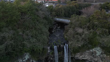 drone aerial view in south korea flying in front of a waterfall over the sea rocky area upwards jeju island