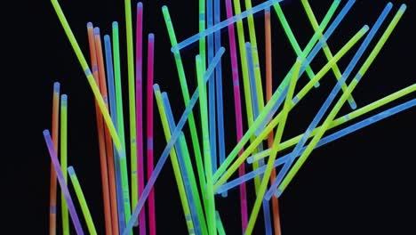 animation of multiple colorful neon glow sticks over black background