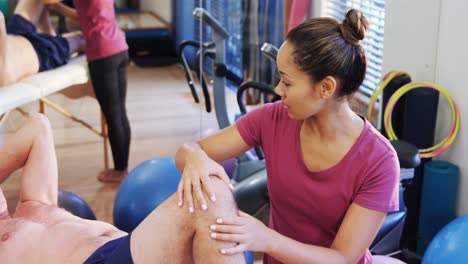 fisioterapeuta dando masaje de rodilla a un paciente anciano 4k