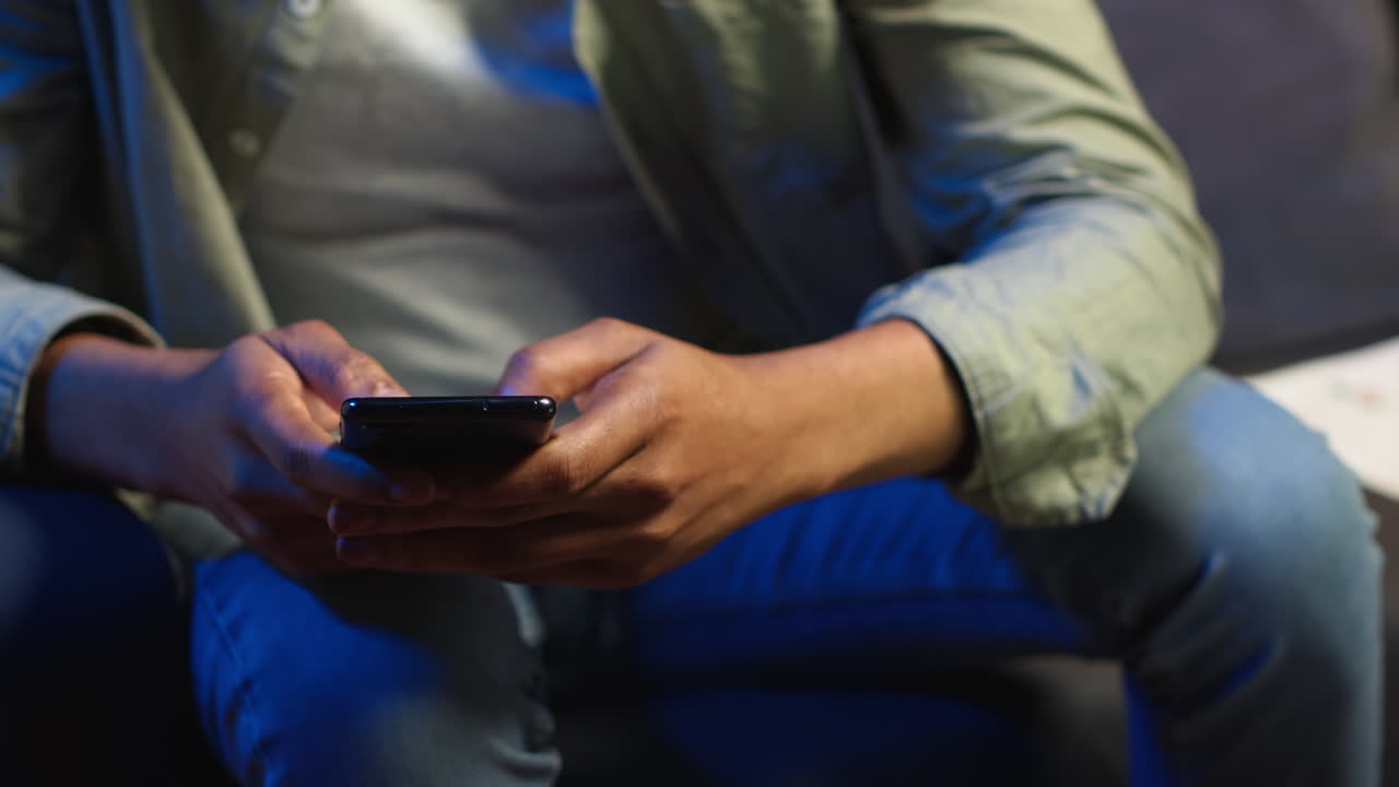 Vertical Video Casual african american man browsing on his smartphone in a comfortable space