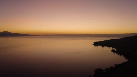 Aerial-shot-descending-towards-Lake-Léman-with-beautiful-sunset-colors-Cully,-Vaud---Switzerland