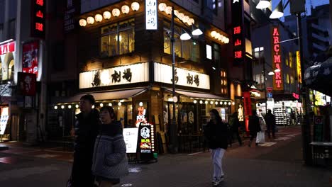 pedestrians walking past illuminated urban buildings