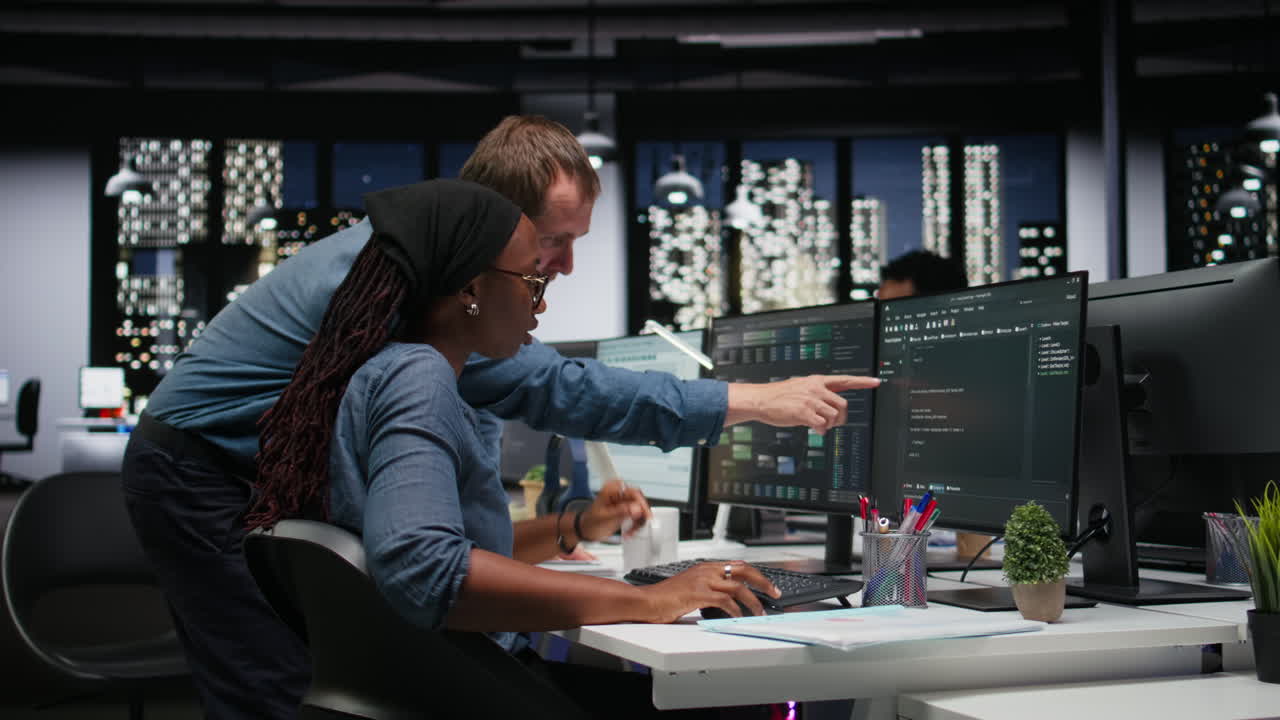 Software Developers Collaborating on Code in Modern Night Office