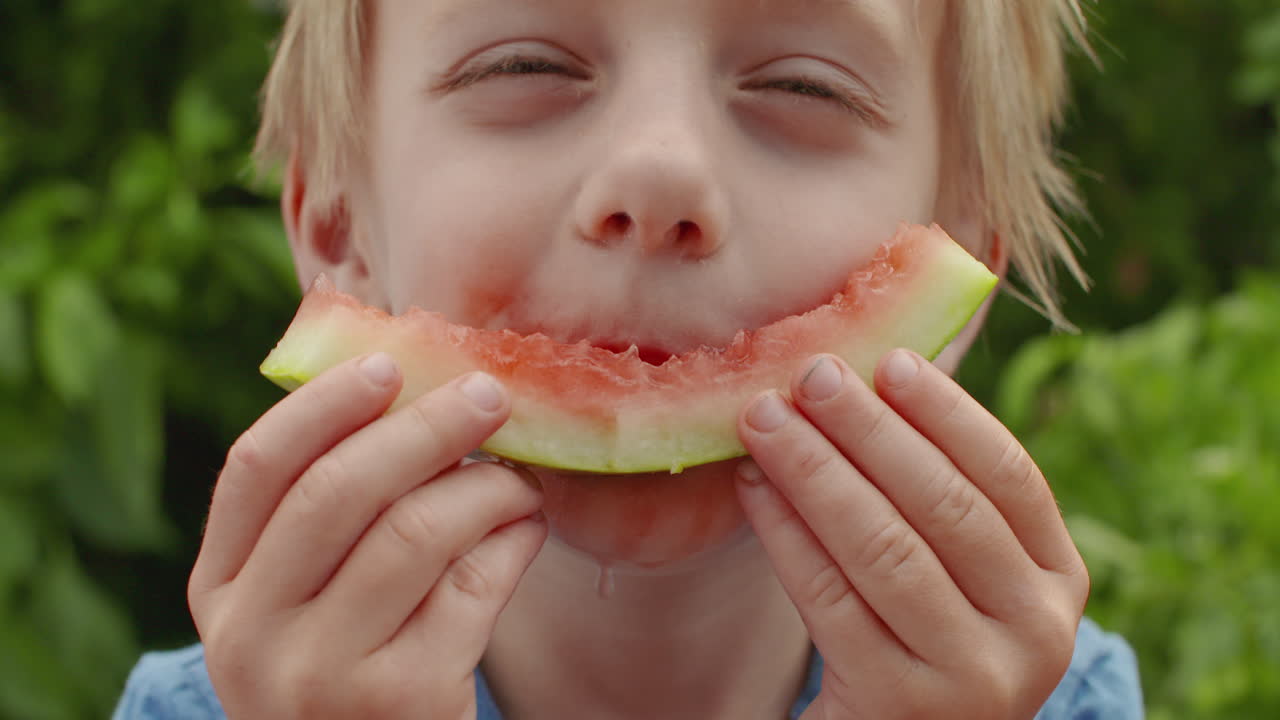 primer plano de un lindo niño sonriendo con una cáscara de sandía