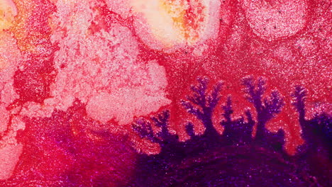 macro shot of violet ink injected into shimmering red-pink ink, gradually pushing through and creating vibrant contrast and organic patterns