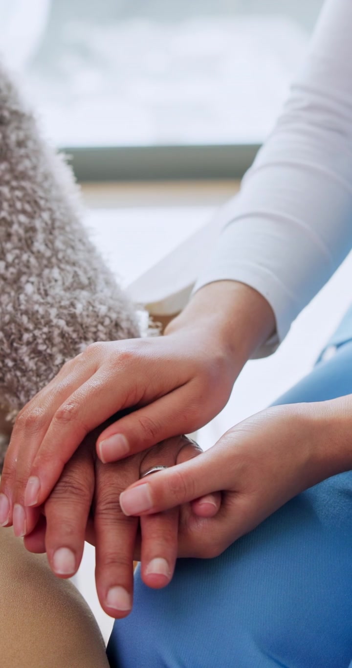 Cuidador sosteniendo las manos de una persona mayor para brindarle consuelo