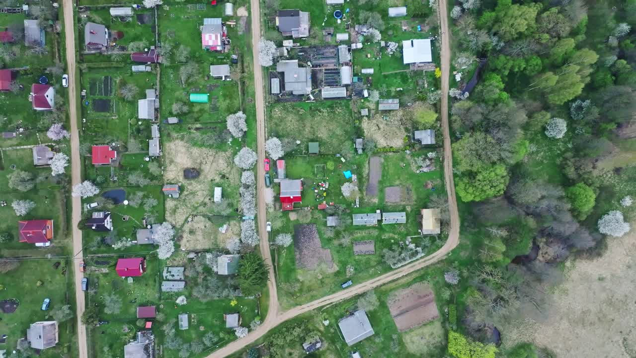 Top down aerial view over Latvian garden plots with sheds paths and green fields
