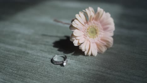 soft pink flower with diamond ring resting on textured fabric