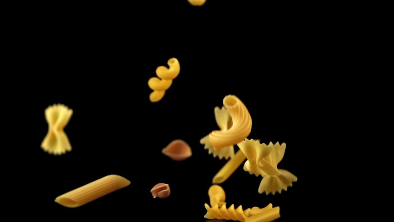 Assortment of Dry Pasta Falling in Slow Motion Against Black Background