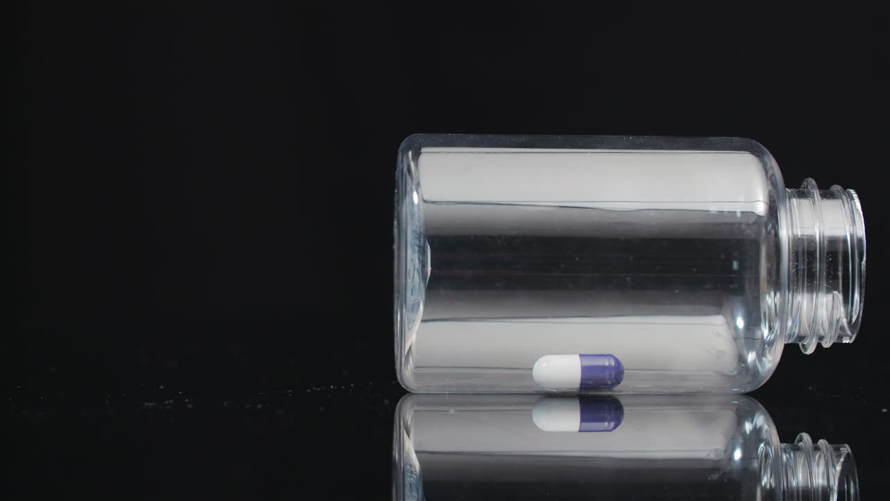 píldora médica única en botella pequeña girando sobre fondo negro 6