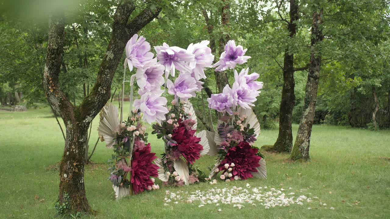 wedding arch with lilac crepe and real flowers in enchanting forest , slider shot.