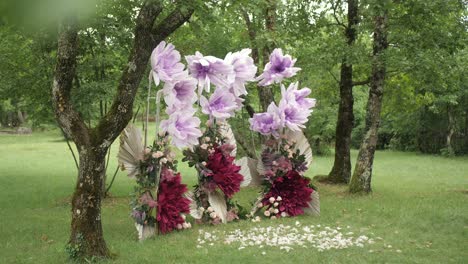 wedding arch with lilac crepe and real flowers in enchanting forest , slider shot.