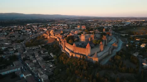 Toma-Aérea-En-órbita-De-La-Famosa-Ciudadela-Medieval-En-Carcasona,-Francia-Durante-La-Puesta-De-Sol