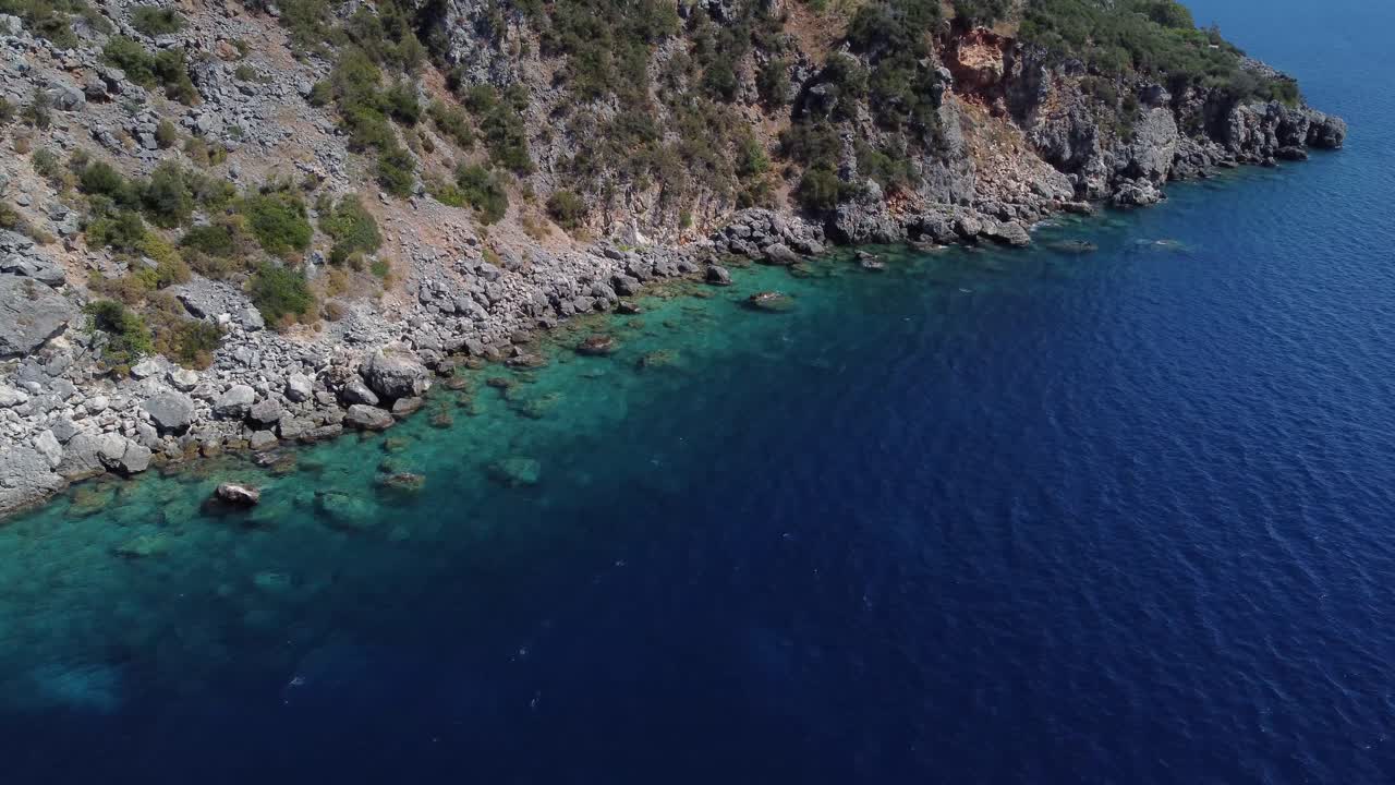 Aerial view of rocky sea shore with calm blue water at Lefkada, Greece, drone shot
