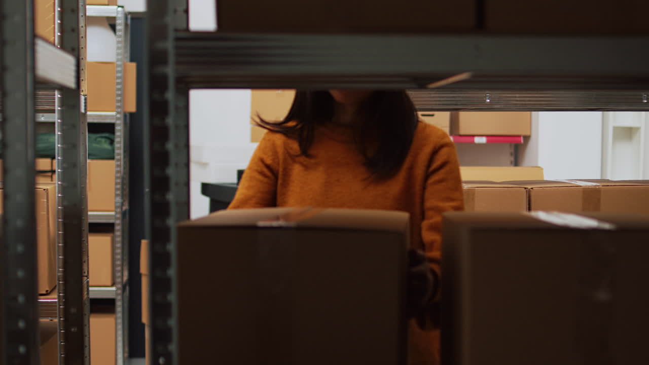 Two women working in a warehouse office with a laptop and boxes