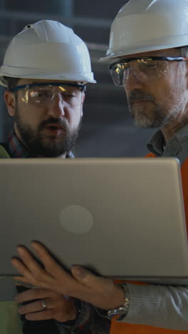 trabajadores de la construcción revisando el proyecto en la computadora portátil