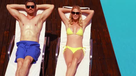 Smiling-couple-sunbathing-on-deck-chairs