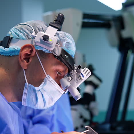 surgeon wearing binocular loupe device carries out the operation. side view close up portrait of a neurosurgeon focused on surgery.