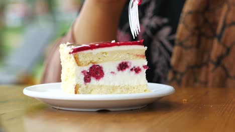 woman eating a slice of raspberry cream cake