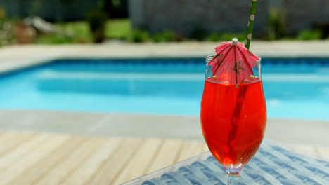 Close-up-of-cocktail-drink-on-a-table-near-swimming-pool-4k