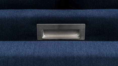 Camera-slowly-zooms-in-brushed-metal-handle-fold-out-bed-with-dark-blue-fabric