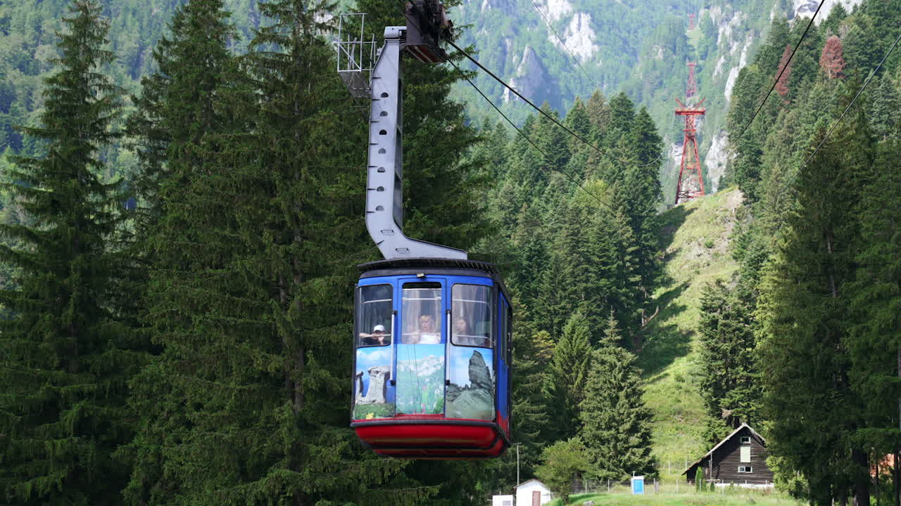 Funivia su montagna boscosa. Una funivia viaggia in alto sopra alberi fitti in una regione montuosa, mostrando paesaggi mozzafiato e cieli sereni