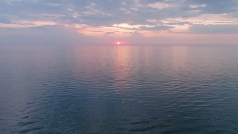 beautiful aerial view of vibrant high contrast sunset over calm baltic sea, clouds at the horizon, karosta war port concrete coast fortification ruins at liepaja, wide drone shot moving forward