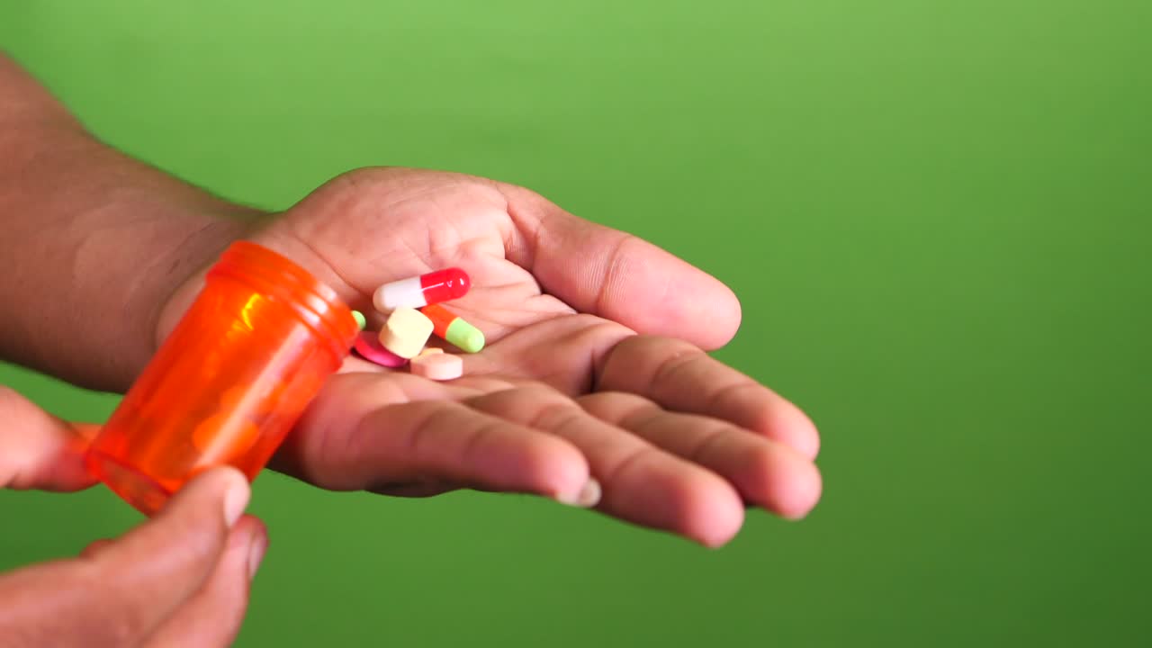 Close up of man hand taking medicine on green screen