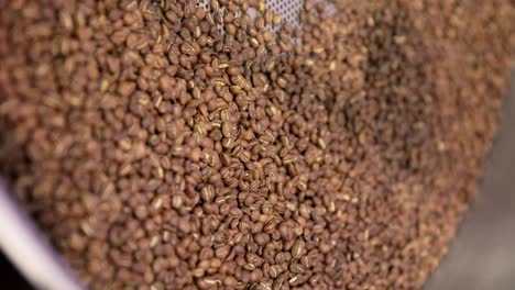 vertical, slow motion coffee beans roasted and spun in large metal container